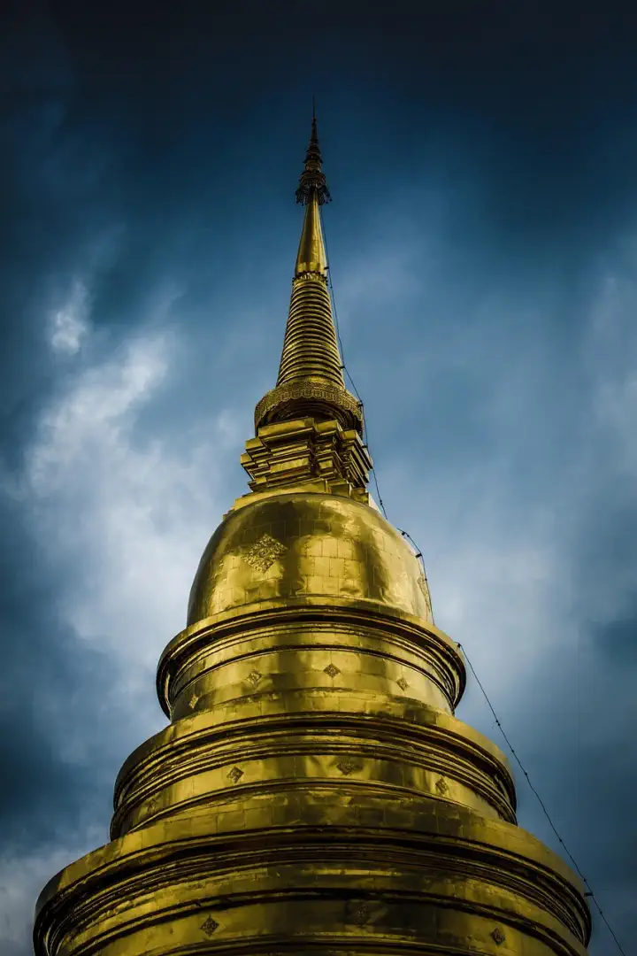 Złota chedi świątyni Wat Suan Dok wznosząca się ku ciemnemu niebu, z widocznymi detalami architektonicznymi